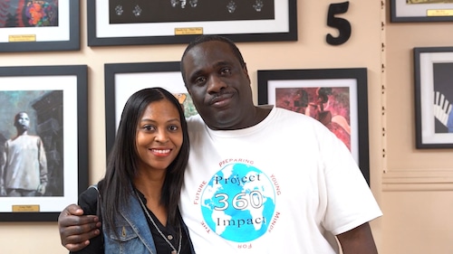 Owner, Wayne Wright (right) and artist, Tasha Fain (left) pose in front of one of the gallery walls in his barbershop, The Wright Cut, in 2019.