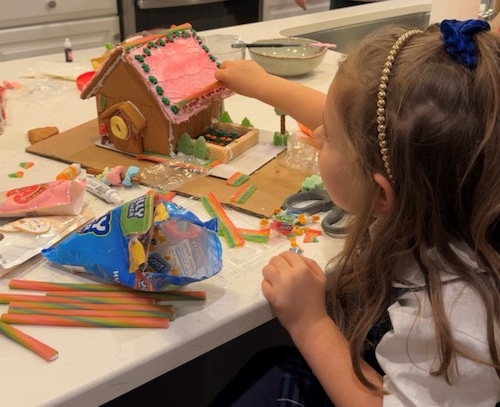 Five year old Violetta Darcangelo carefully presses candy into the roof of her gingerbread house.